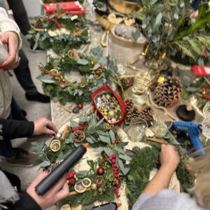 Šventinio dekoravimo dirbtuvės, kuriose žmonės kuria žiemos ir Kalėdų vainikus, naudojant įvairius spygliuočius, adatą, kaštonus, vakarines uogas ir dekoro elementus, siekiant sukurti jaukią šventinę atmosferą.